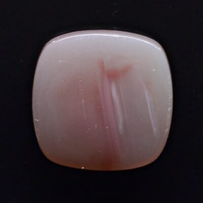 A square piece of pink jade on a black surface.