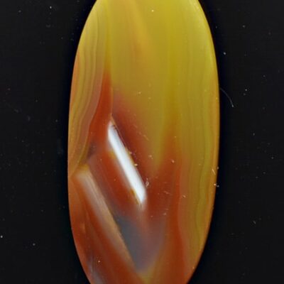 A yellow and orange agate cabochon on a black background.