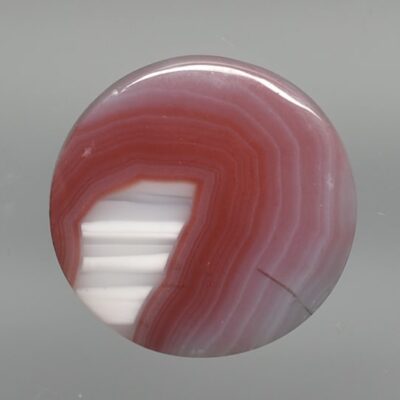 A red and white agate cabochon on a white background.