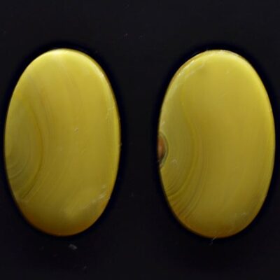 A pair of yellow agate studs on a black surface.