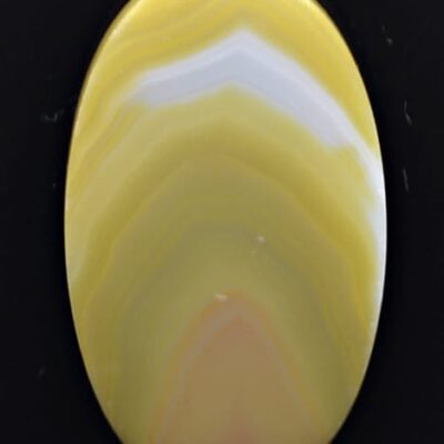 A yellow and white agate cabochon on a black background.