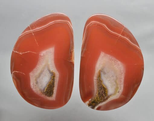 A pair of red agate slices on a white surface.
