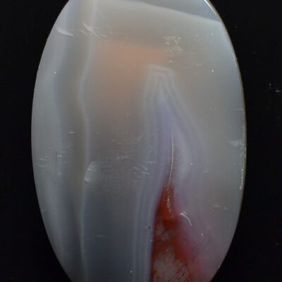 A white and red agate pendant on a black background.
