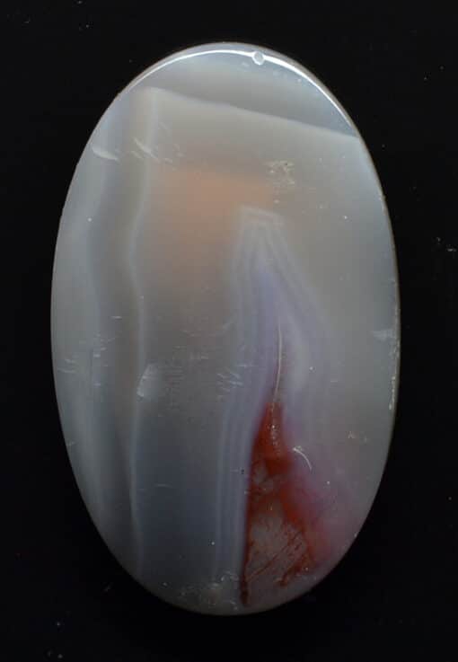 A white and red agate pendant on a black background.