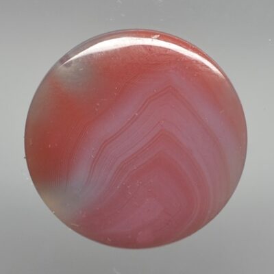 A red and white agate button on a white background.