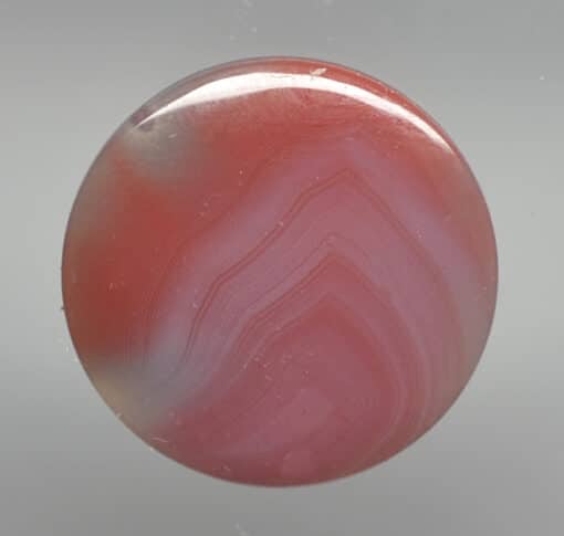 A red and white agate button on a white background.