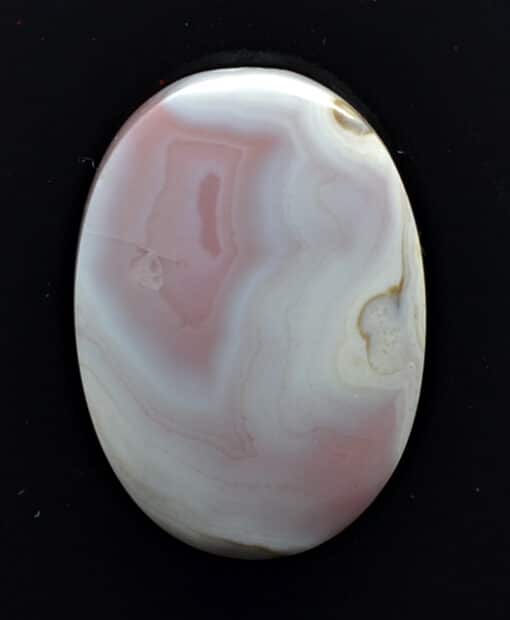 A pink and white agate pendant on a black background.