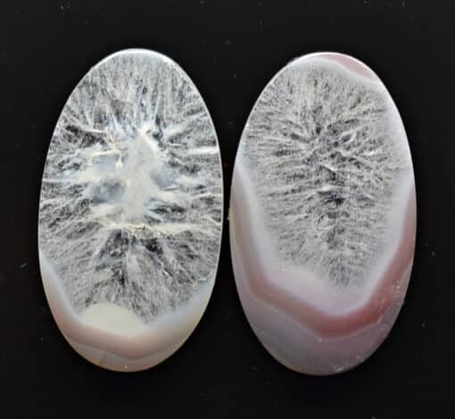 Two oval pieces of agate on a black surface.