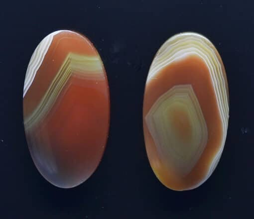 Two oval agate stones on a black surface.