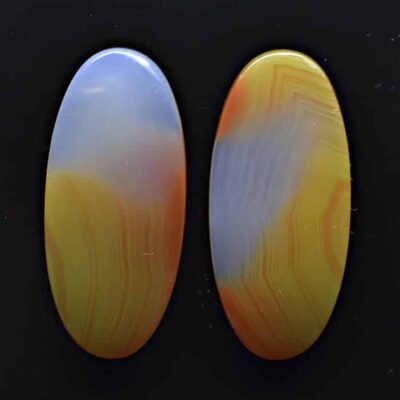 A pair of yellow and orange agate ovals on a black surface.
