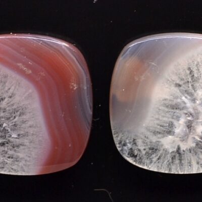 Two pieces of red and white agate on a black surface.