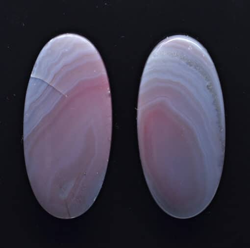 Two pink agate oval cabochons on a black background.