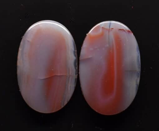 Two oval agate cabochons on a black surface.