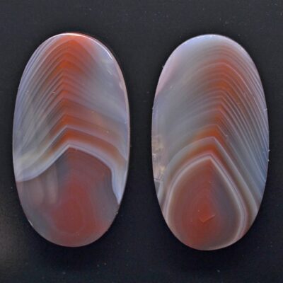 Two oval pieces of agate on a black surface.
