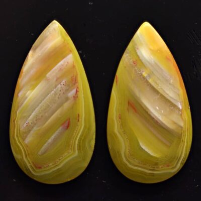 Two yellow agate teardrops on a black surface.