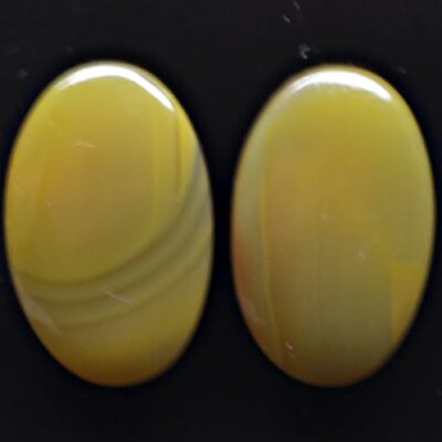 Two yellow agate oval cabochons on a black background.