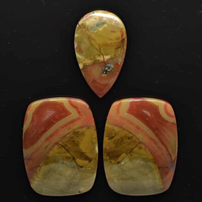 Three pieces of red and yellow jasper on a black background.
