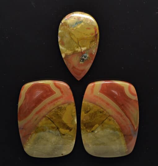 Three pieces of red and yellow jasper on a black background.