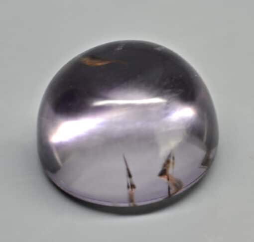 A purple amethyst stone on a grey surface.