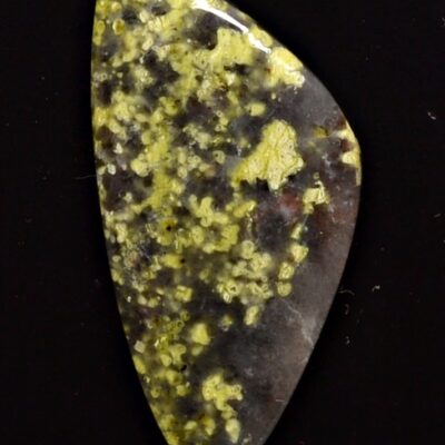 A piece of yellow and green jasper on a black surface.