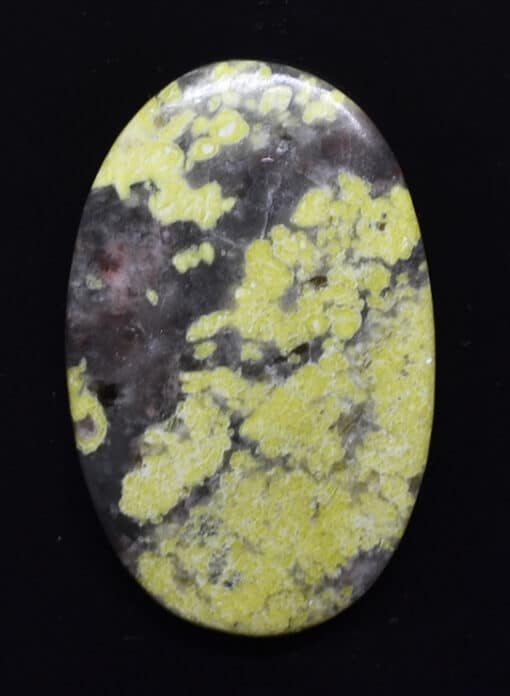 A yellow and black stone cabochon on a black background.