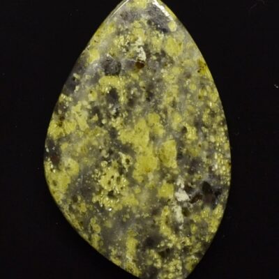 A piece of yellow jasper on a black surface.