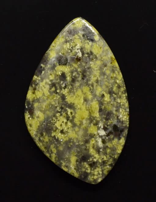 A piece of yellow jasper on a black surface.