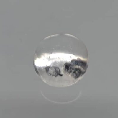 A clear quartz ball on a gray surface.