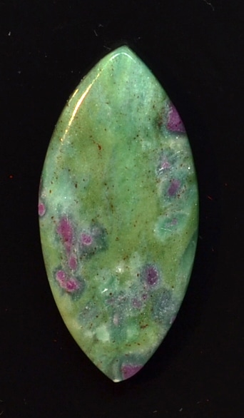 A green and purple stone pendant on a black surface.