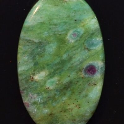 A green jade oval cabochon on a black background.