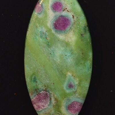 A green and purple stone pendant on a black surface.