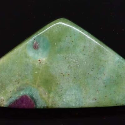 A green and purple stone triangle on a black surface.