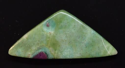A green and purple stone triangle on a black surface.