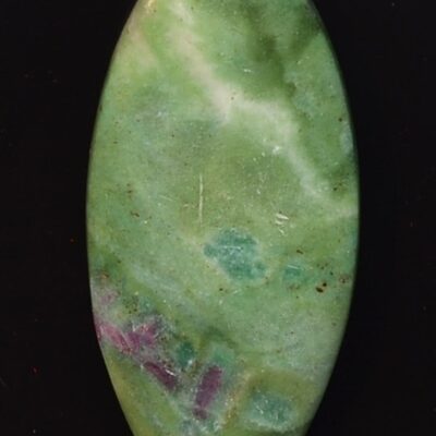 A green jade pendant on a black surface.