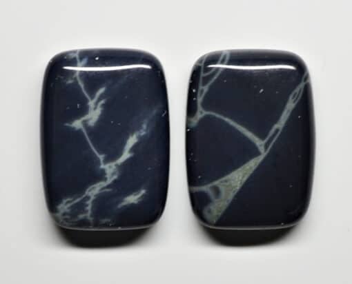 Two black and white marble cabochons on a white surface.
