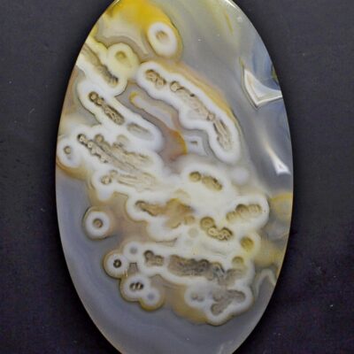 A yellow and white agate pendant on a black surface.