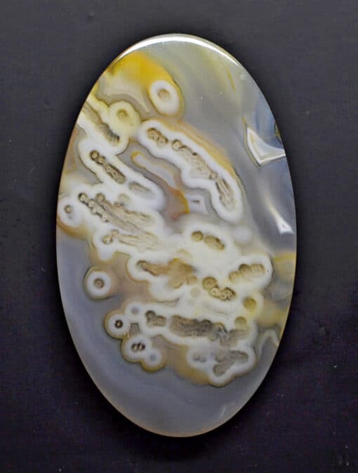 A yellow and white agate pendant on a black surface.