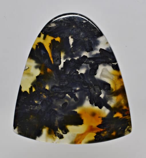 A black and yellow agate pendant on a white surface.