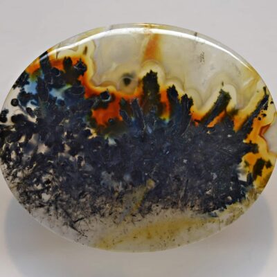 A round piece of agate with black and orange paint on it.