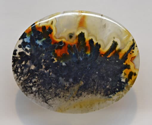 A round piece of agate with black and orange paint on it.