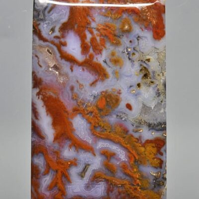 A piece of agate with orange and brown paint on it.