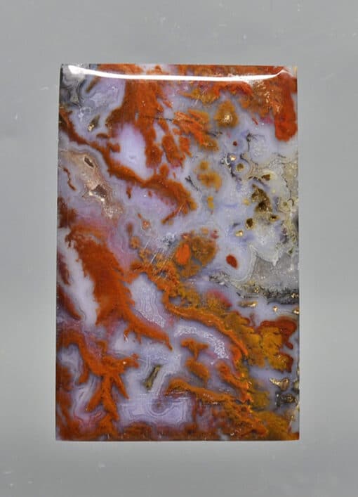 A piece of agate with orange and brown paint on it.