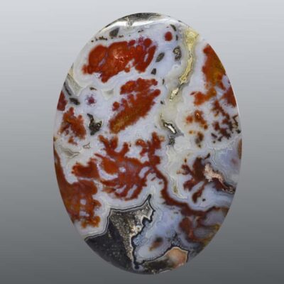 A red and white agate cabochon on a gray background.