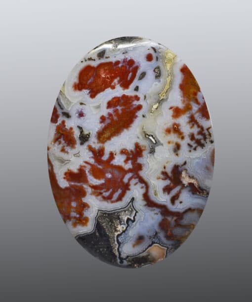 A red and white agate cabochon on a gray background.