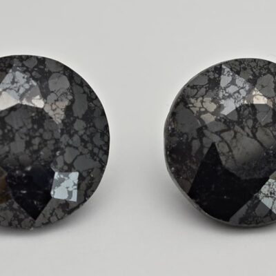 A pair of black diamond studs on a white surface.
