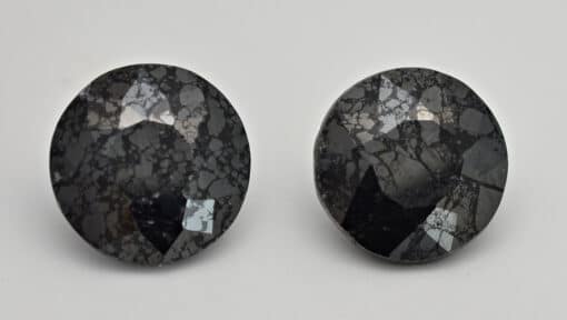 A pair of black diamond studs on a white surface.