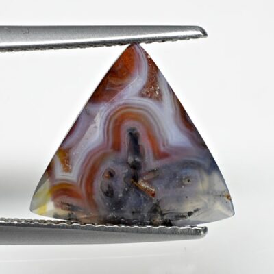 A triangle shaped agate stone with a pair of pliers.