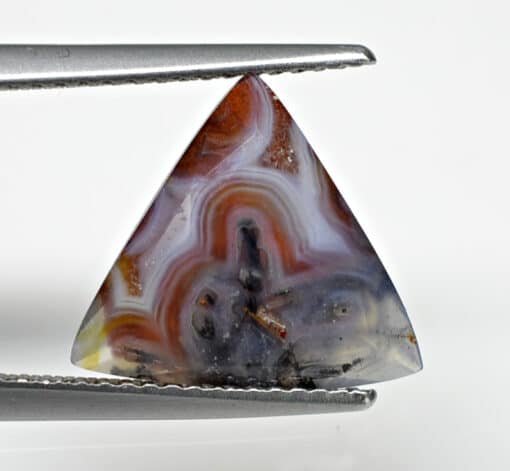 A triangle shaped agate stone with a pair of pliers.