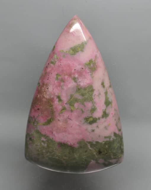 A pink and green stone triangle on a white background.