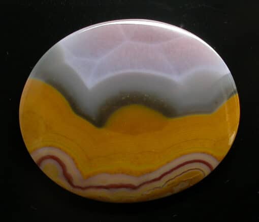 A round piece of agate with a yellow and orange design.